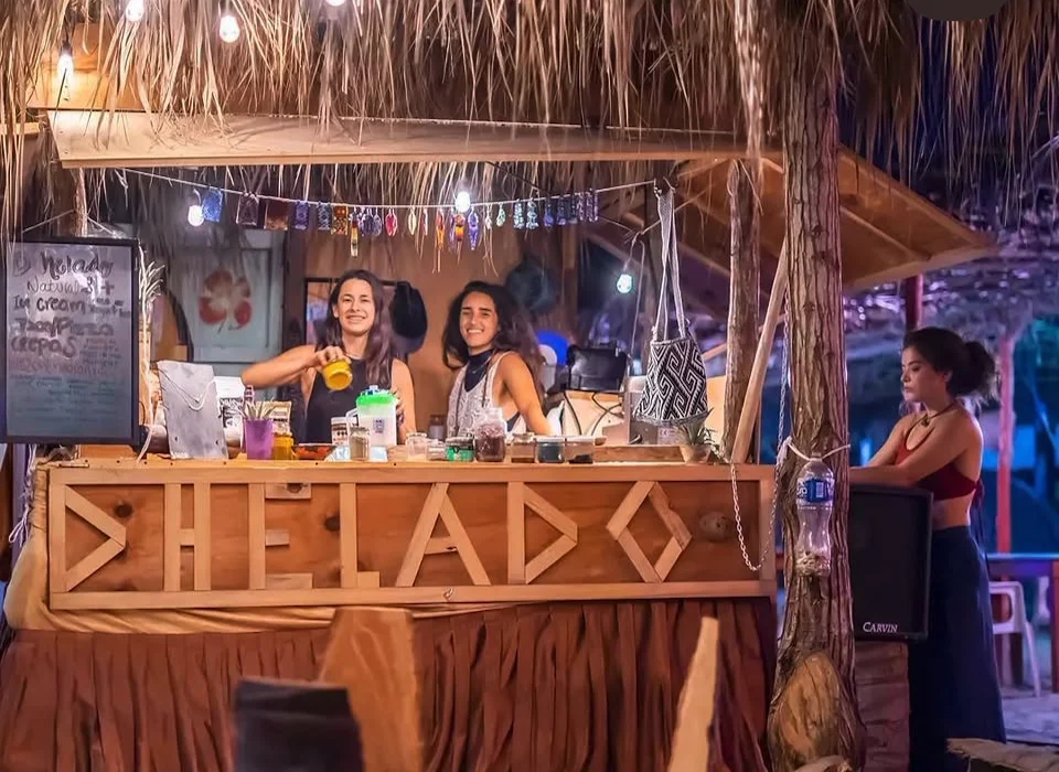 The palm-roofed ice cream stand on the beach in Oaxaca, lit at dusk.
