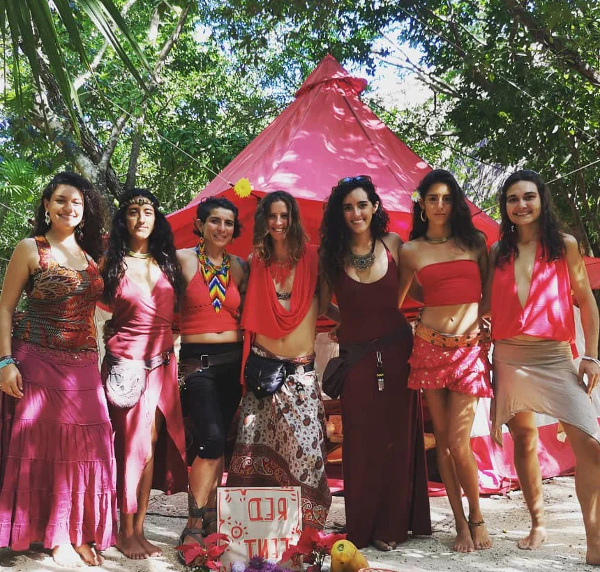 The Red Tent at Cosmic Convergence: a circle of women in red, standing in front of the tent in the jungle.
